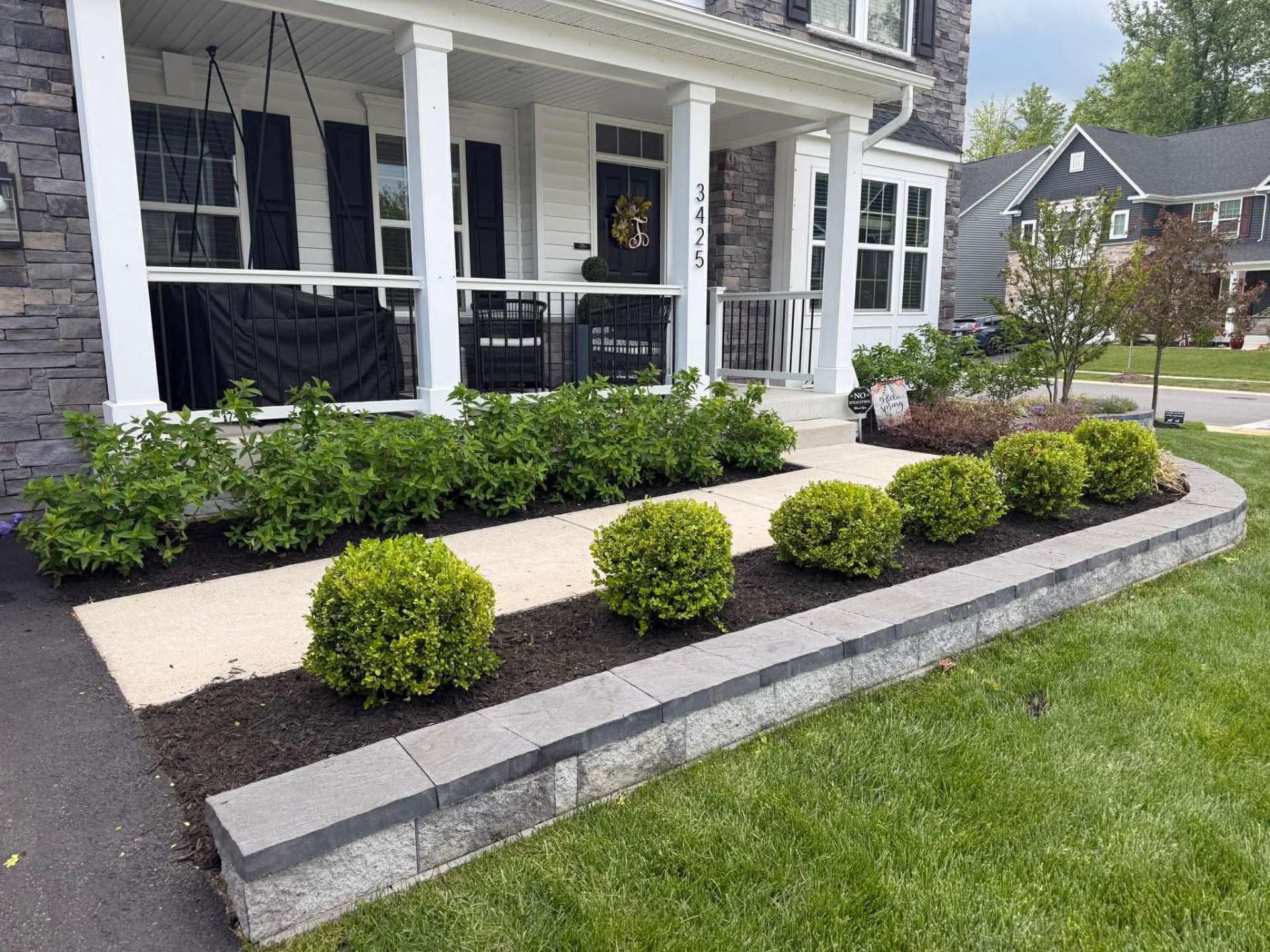 Front porch landscape with fresh mulch, trimmed shrubs, and clean edging